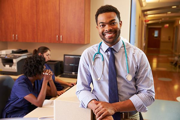 A doctor standing at a reception desk in a GP surgery